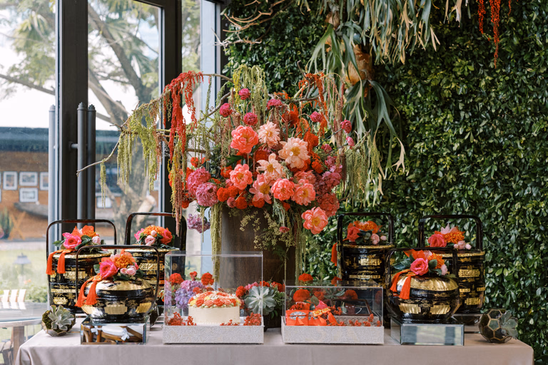 Dessert display of fresh fruit and blooms in front of a living flower wall