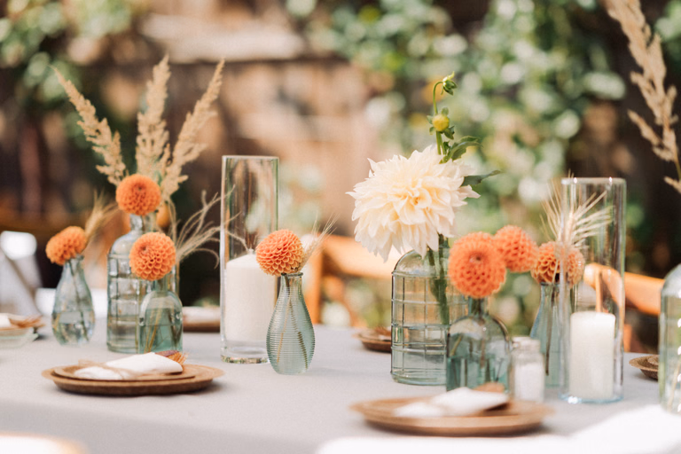 Table setting with bud vases of dahlias and dried grasses